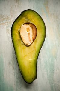 Rustic looking avocado laying on a table cut in half