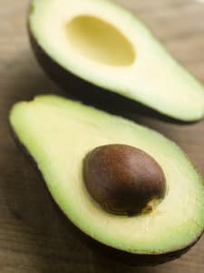 Open face avocado laying on a table with seed in one side