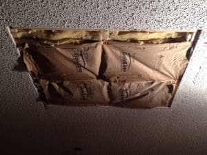 A hole in the ceiling with insulation stuffed in it.