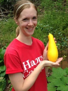 Jenn holds her first yellow squash harvested from our homestead