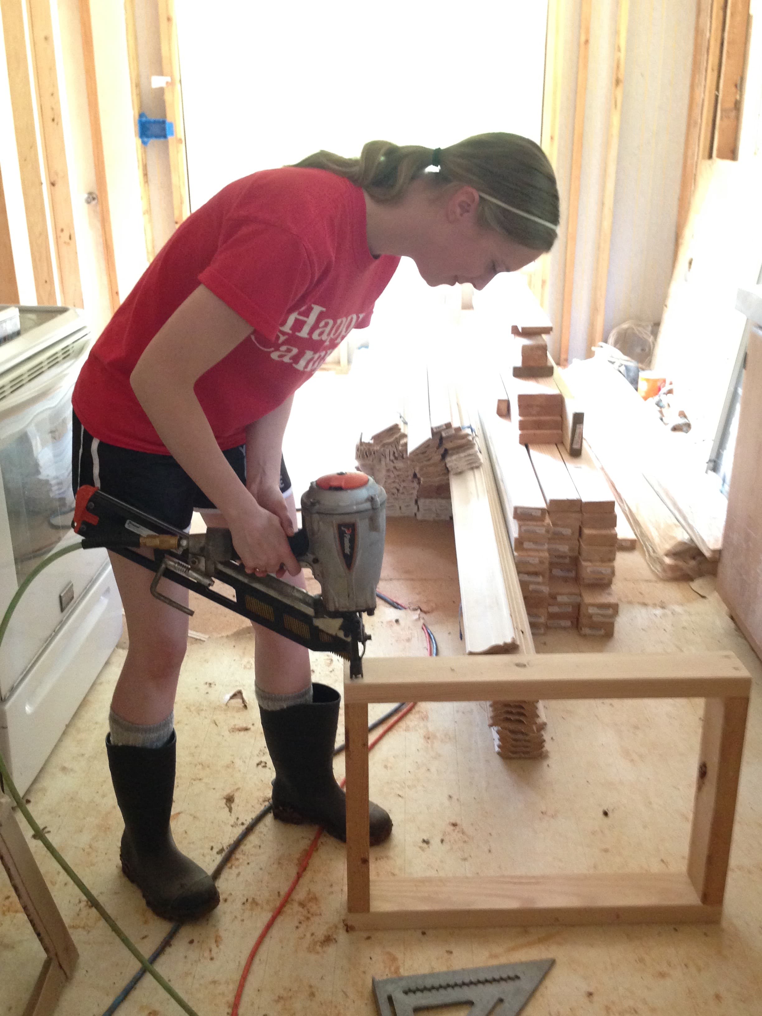 Jenn using a framing nail gun to build the box for one of our wall mounted AC units.